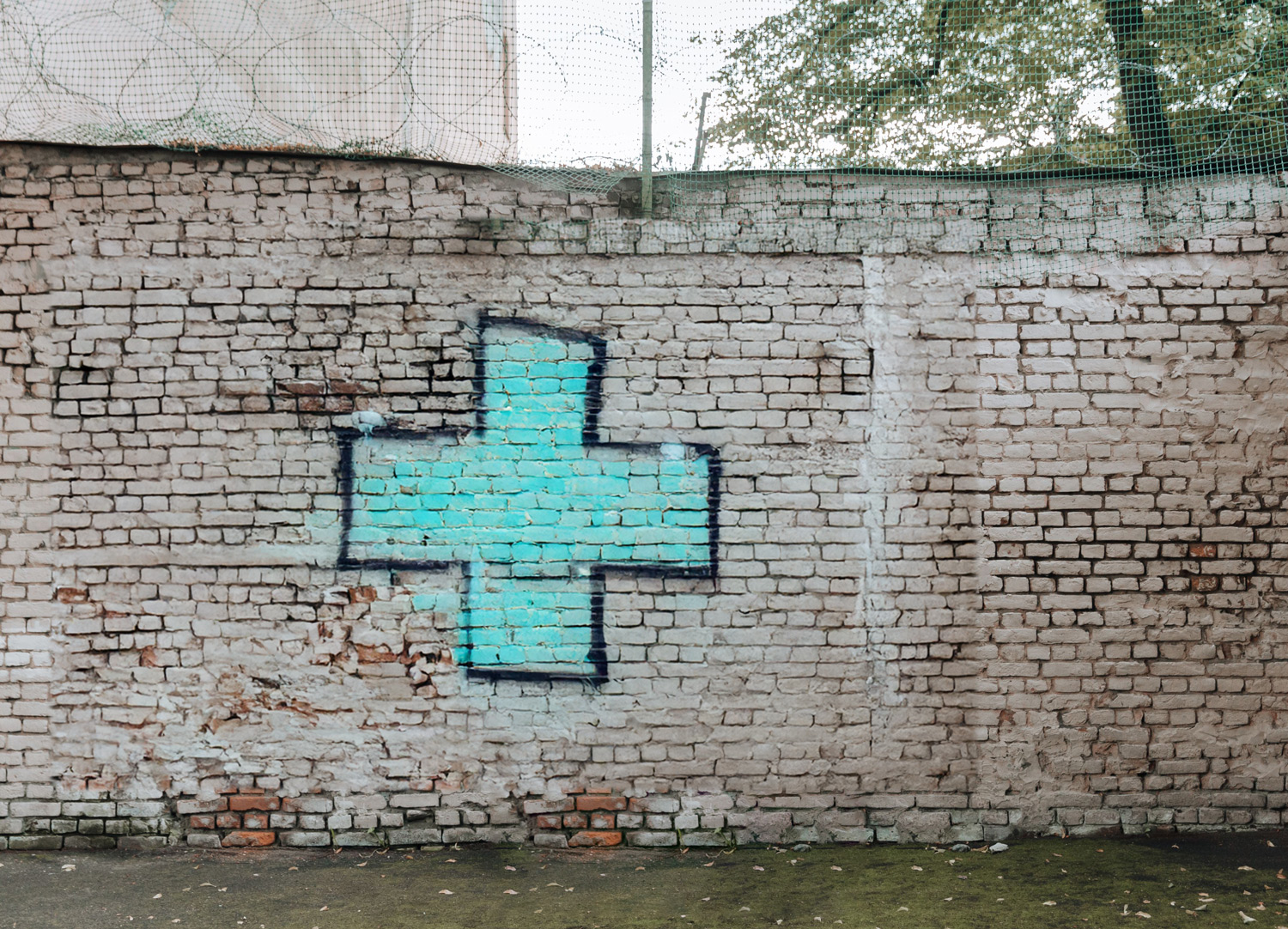 Groen grafittikruis op een vervallen muur